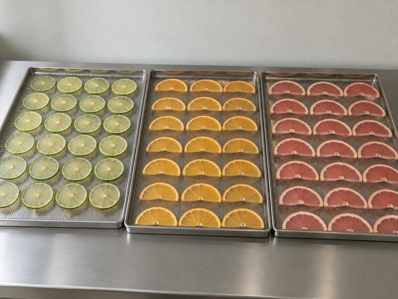Trois grilles chargées : rondelles de citron vert, demi-rondelles d'orange et de pamplemousse